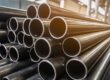 Stacks of round steel tubes are arranged horizontally. The open ends of the tubes face toward the viewer.
