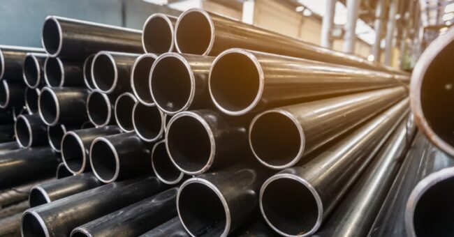 Stacks of round steel tubes are arranged horizontally. The open ends of the tubes face toward the viewer.
