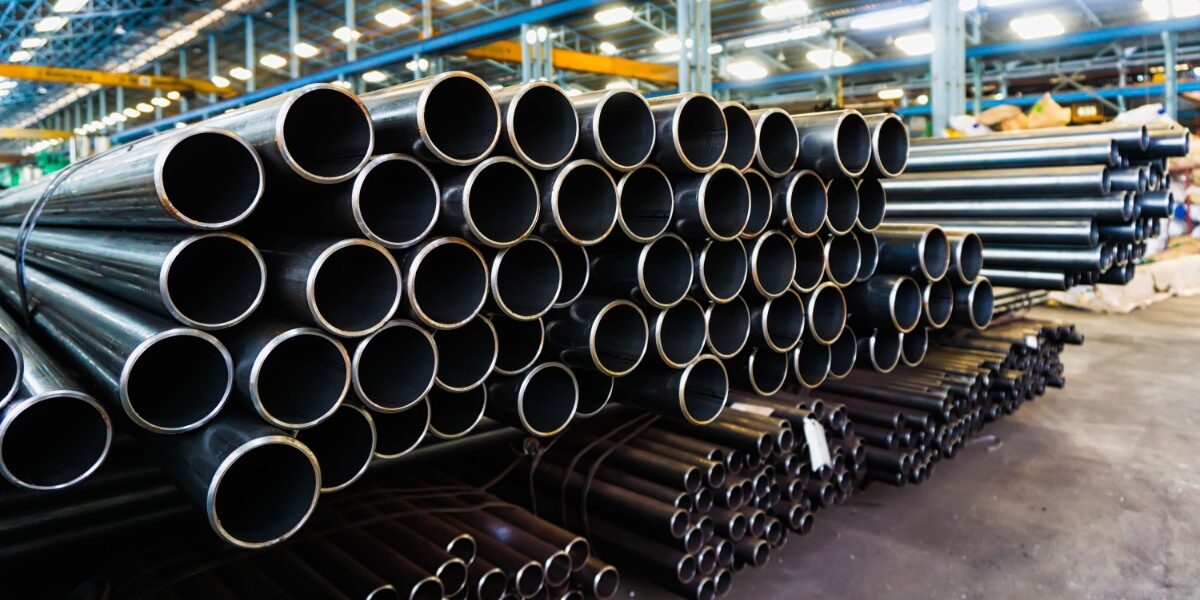 Hot-Dip Pipe vs Pre-Galvanized Steel Tube Large and small steel pipes are stacked in organized bundles inside a manufacturing facility. The ends face the viewer.